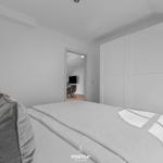 Schlafzimmer mit Bett, Kleiderschrank und Blick in Wohnbereich.