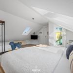 Schlafzimmer mit Dachschrägen, zwei Betten und Dachfenstern.