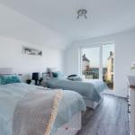 Zwei Betten mit hellblauen Bettwäschen und einem Balkon mit Blick.