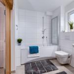 Badezimmer mit Badewanne, Dusche und Waschbecken. Fenster mit Pflanze.