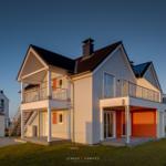 Modernes Ferienhaus mit Balkon und Garage. Außenbereich mit Grünfläche.
