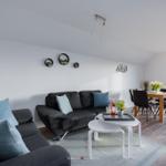 Wohn- und Essbereich mit Sofa, Tisch und Balkonansicht.