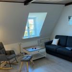 Wohnzimmer mit Sofa, Sessel und Dachfenster.