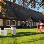 Rotes Backsteingebäude mit Strohdach und Garten mit Liege und Tisch.