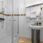 Badezimmer mit Dusche, Waschbecken und Spiegelschrank.