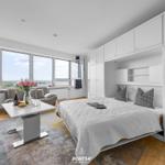 Ein Raum mit Bett, Sofa und großem Fenster mit Blick auf die Landschaft.