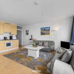 Wohnküche mit Sofa, Tisch und Blick aus Fenster.