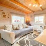 Wohnraum mit Sofa, Fenstern und Holzwänden