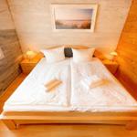 Schlafzimmer mit Holzwand, Bett und Nachttischen