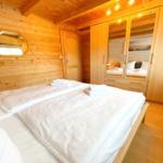 Schlafzimmer mit Holzwand, Bett und Kleiderschrank