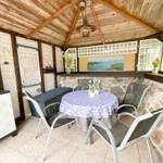 Gepflegter Sitzbereich mit Tisch, Stühlen und Steinwand unter Holzdecke.