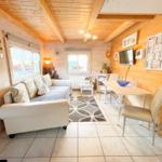 Wohn- und Essbereich mit Sofa, Tisch und TV an Holzwänden.