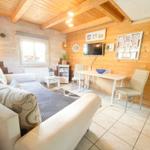 Wohnraum mit Sofa, Tisch und Fernseher an Holzwand