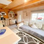 Wohn- und Küchenbereich mit Sofa, Tisch und Holzdecke.