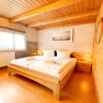 Schlafzimmer mit Holzwand, Bett und Fenster.