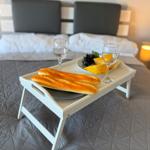 Ein Bett mit einem Tablett, auf dem Brot, Käse, Trauben und zwei Gläser stehen.