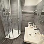 Badezimmer mit Dusche, Waschbecken und Spiegelschrank.