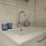 Waschbecken mit Wasserhahn, Seifenspender und zwei Gläsern mit Seesternmotiv.