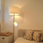 Ein Bett mit Kissen, Nachttisch und Stehlampe neben dem Fenster.