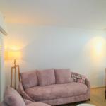 Ein Wohnzimmer mit rosa Sofa, Sessel und runder Tisch.