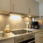 Küche mit Induktionskochfeld, Dunstabzug und Kaffeemaschine.