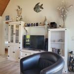 Wohnzimmer mit Fernseher, Schränken und Sitzgelegenheit. Sehenswert: Wanddekoration und Schiffsmotiv.