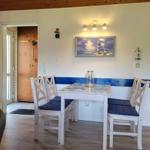 Essbereich mit Tisch, Stühlen und Wandbild. Durchgang zur Küche und Eingangstür.