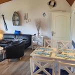 Wohn- und Essbereich mit Sofa, Tisch und Küchenzeile. Wanddekoration mit Segelbootmotiven.