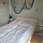 Schlafzimmer mit Bett, Nachttischen und maritimen Wanddekoration.