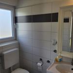 Badezimmer mit Toilette, Waschbecken und Fenster.