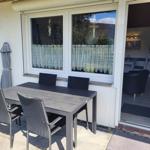 Terrasse mit Tisch und Stühlen, Schiebetür zum Innenraum mit Sitzgelegenheiten.