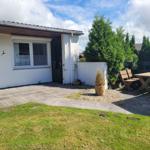 Hinterhof mit Terrasse, Garten und Holztisch mit Bänken.