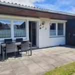 Terrasse mit Tisch und Stühlen vor einem Haus mit Fenstern und Tür.