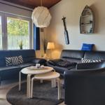 Ein Wohnzimmer mit zwei schwarzen Sofas, einem runden Tisch und Fenstern.