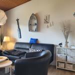 Wohnzimmer mit Sofa, Sessel und dekorativen Meeresmotiven an der Wand.