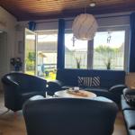 Wohnzimmer mit blauem Sofa, Sitzgelegenheiten und Blick auf den Garten.