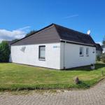 Weiße Ferienwohnung mit Dach und Garten. Satellitenschüssel auf dem Dach.