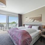 Schlafzimmer mit Balkon und Bett mit Musterdecke.