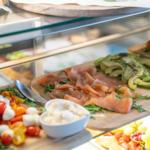 Frühstücksbuffet mit Lachs, Avocado und Käse auf Holzbrettern.