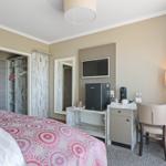 Schlafzimmer mit Bett, Schreibtisch, Fernseher und Kleiderschrank.