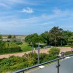 Terrasse mit Blick auf grünen Park und Strand