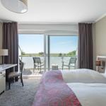 Schlafzimmer mit Balkon, Bett, Schreibtisch und Kühlschrank.