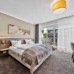 Schlafzimmer mit Doppelbett, Schreibtisch und Balkonansicht.