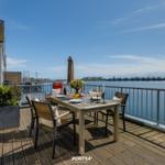 Terrasse mit Tisch, Stühlen und Meerblick. Tisch gedeckt mit Obst und Kerzen.