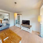 Wohnzimmer mit Sofa, Fernseher und Küchenbereich im Hintergrund.