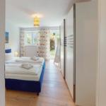 Zimmer mit zwei Betten, Holzboden und Fenster mit bunten Vorhängen.