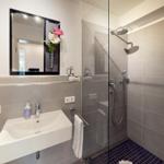 Badezimmer mit Dusche, Waschbecken und Spiegel.