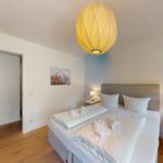 Schlafzimmer mit Bett, Nachttischen und Decke. Hängelampe und Wandbild.