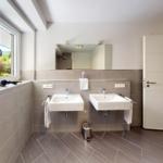 Badezimmer mit zwei Waschbecken, Spiegel und Fensterblick auf Garten