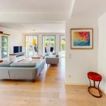 Wohnbereich mit Sofa, Fernseher und Blick auf die Terrasse.